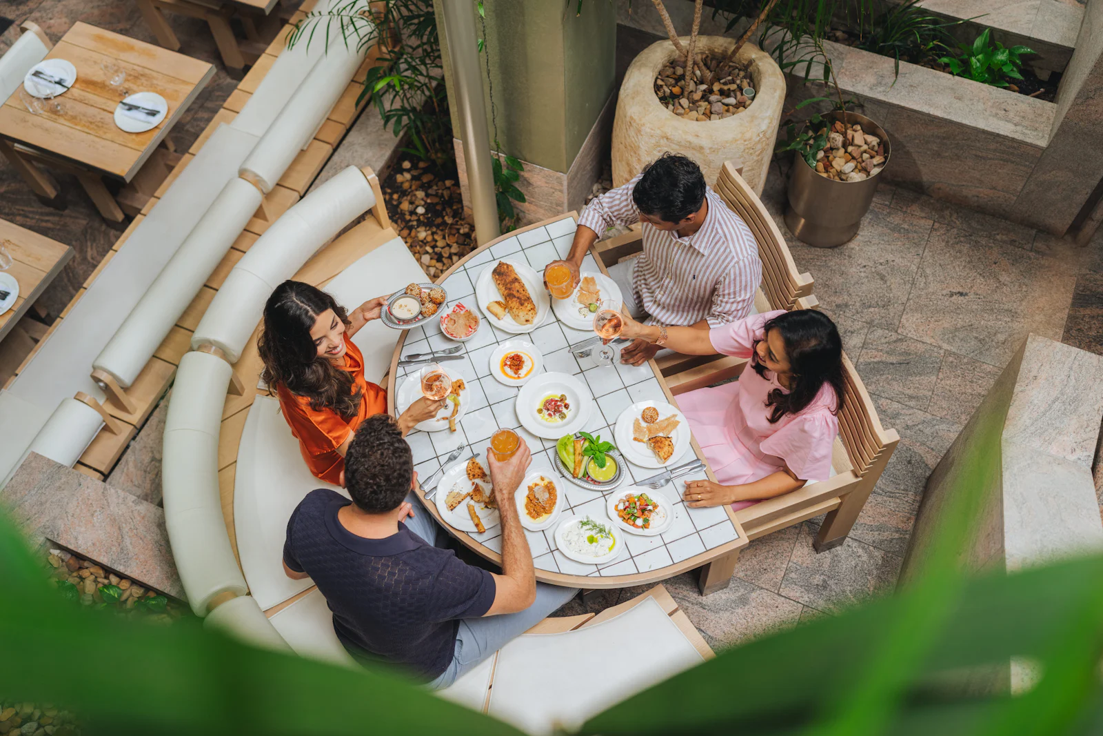 Vier Freunde essen gemeinsam an einem Tisch im Freien, von oben fotografiert