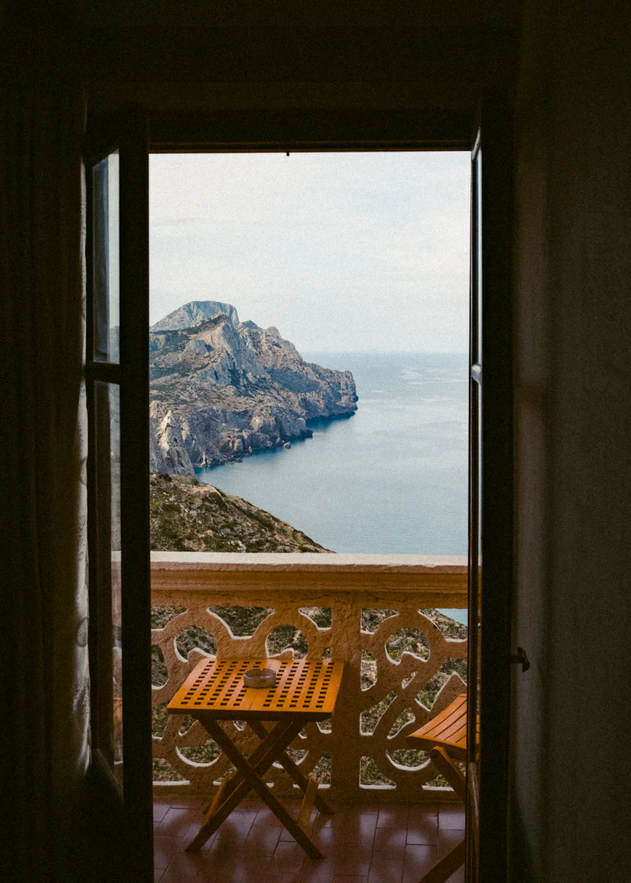 Offene Balkontür mit Blick auf eine Felsküste und das Meer